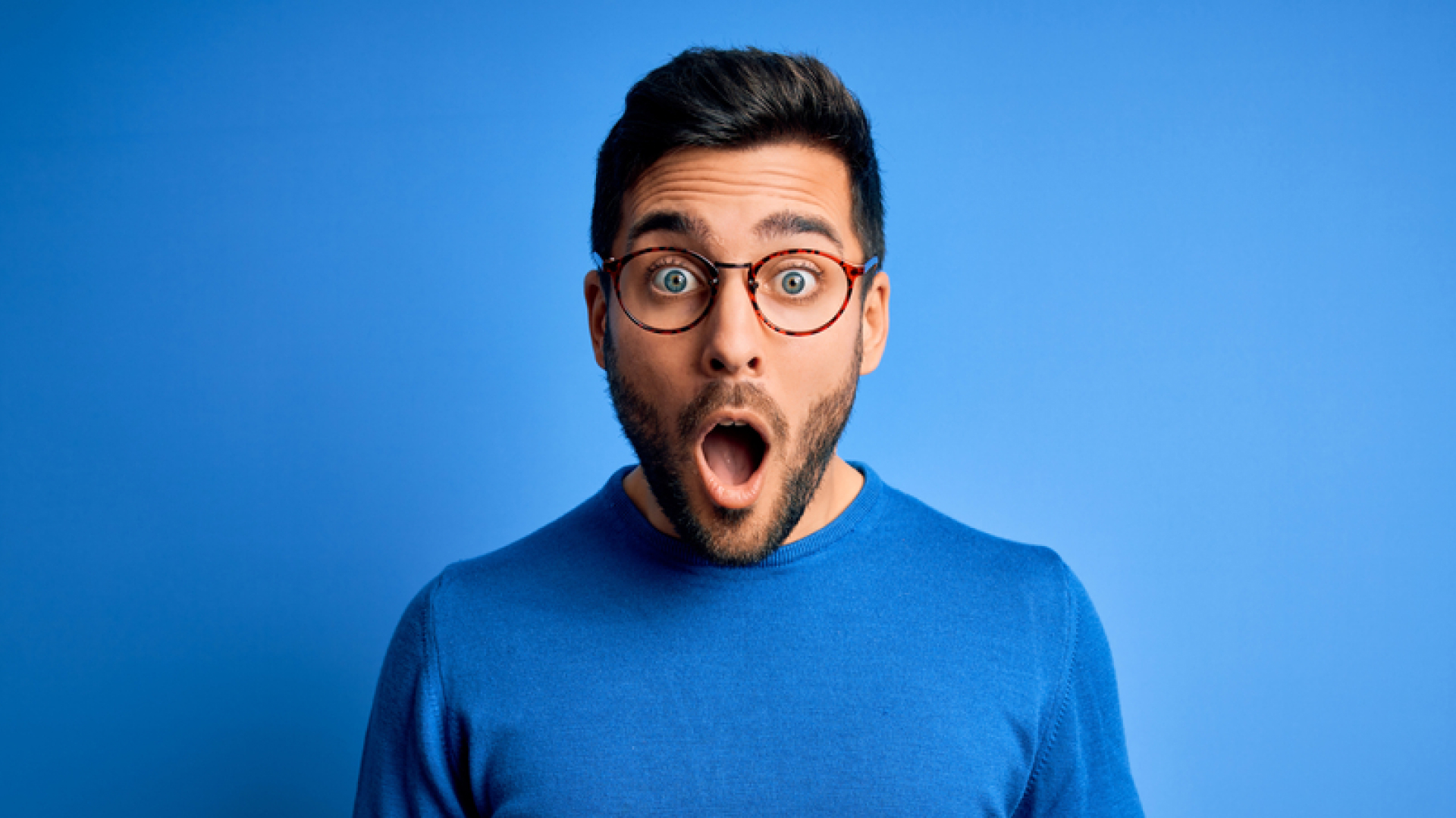 Shocked man in blue in front of blue background